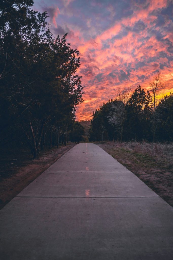 Sunset on a sidewalk with park trees in Austin, Texas with red cloudy sky
